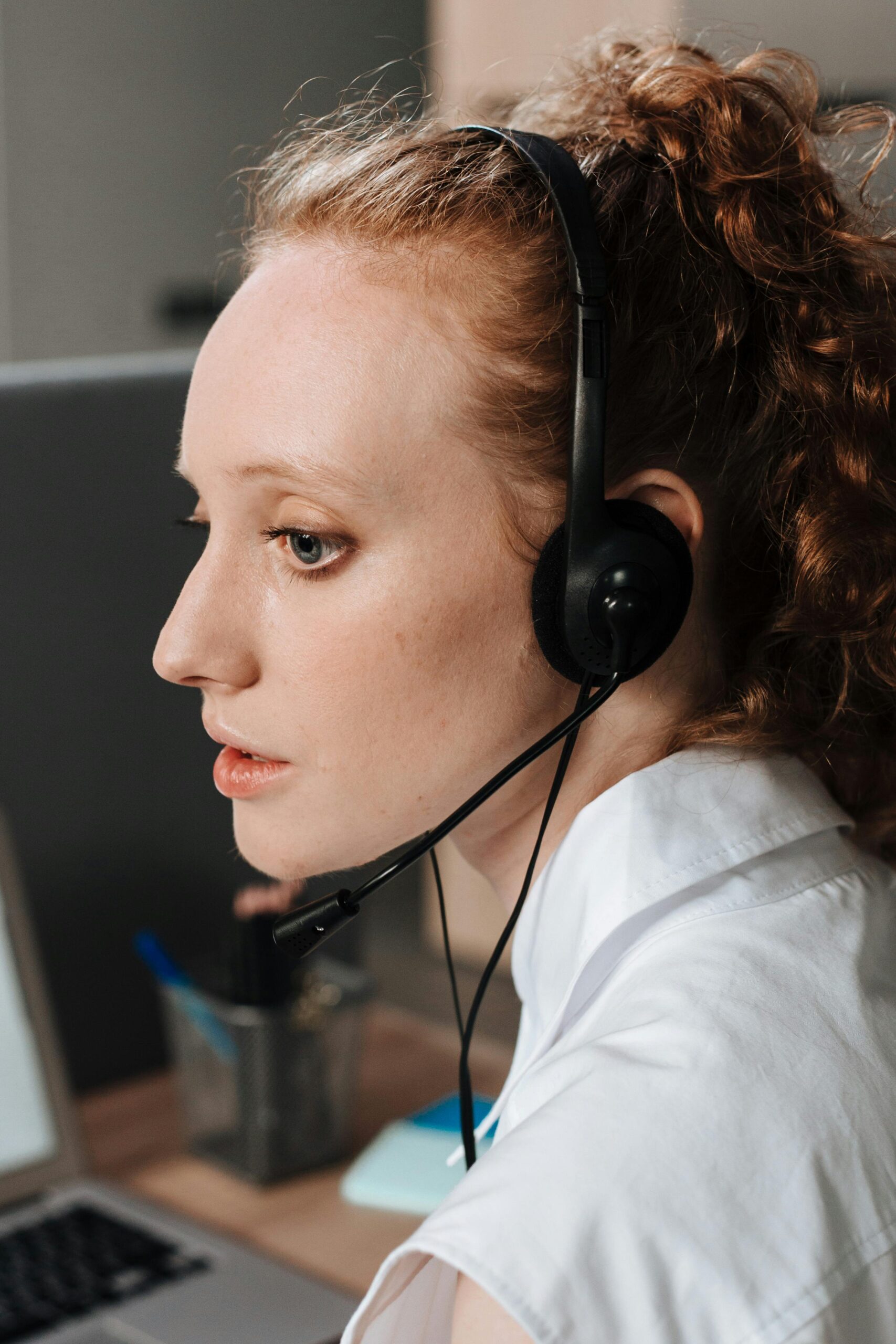 Home Side view of a woman using a headset while working indoors, conveying focus and professionalism.